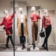Retail store window featuring full-body mannequins styled with apparel