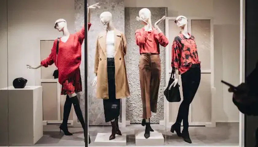 Retail store window featuring full-body mannequins styled with apparel
